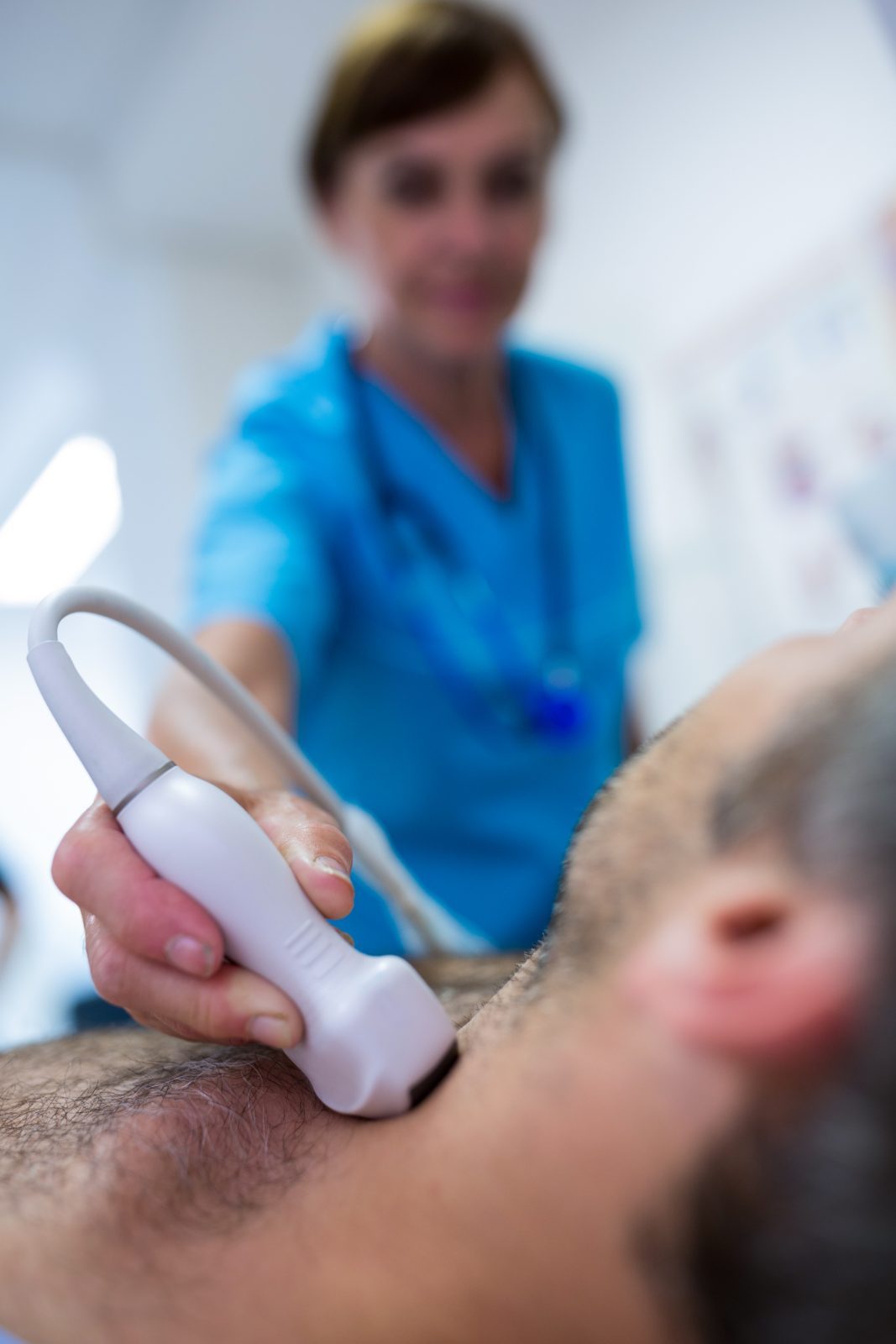 Médica faz ultrassom no pescoço de um paciente